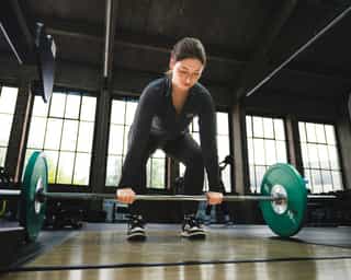 Frau beim Training mit Langhantel im Trainingsbereich von Physiosport Köln..