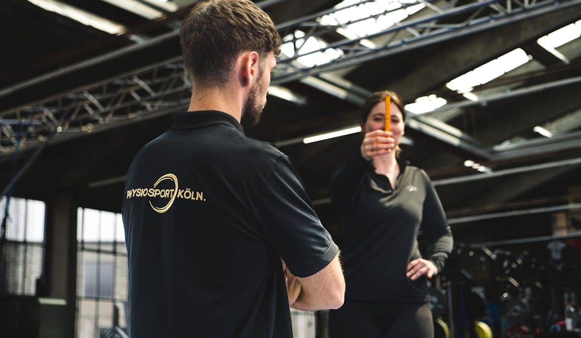 Physiotherapeut von PhysioSport mit einer Patientin. Er erläutert die Grundlagen zum Neuroathletiktraining.