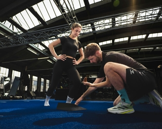 Trainer mit Frau bei Erläuterung der richtigen Fußstellung bei PhysioSport Köln.
