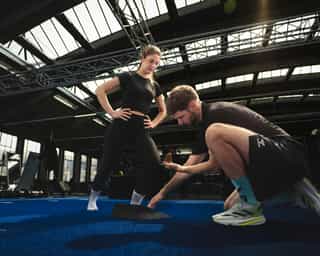 Trainer mit Frau bei Erläuterung der richtigen Fußstellung bei PhysioSport Köln.