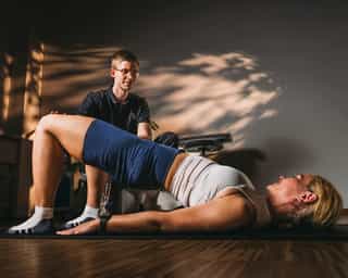 Physiotherapeut von PhysioSport Köln unterstützt Patientin beim Training der Rumpfmuskulatur.