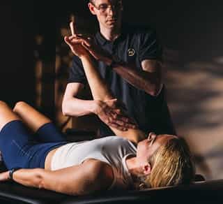 Physiotherapeut von PhysioSport Köln behandelt eine Patientin mit Krankengymnastik.