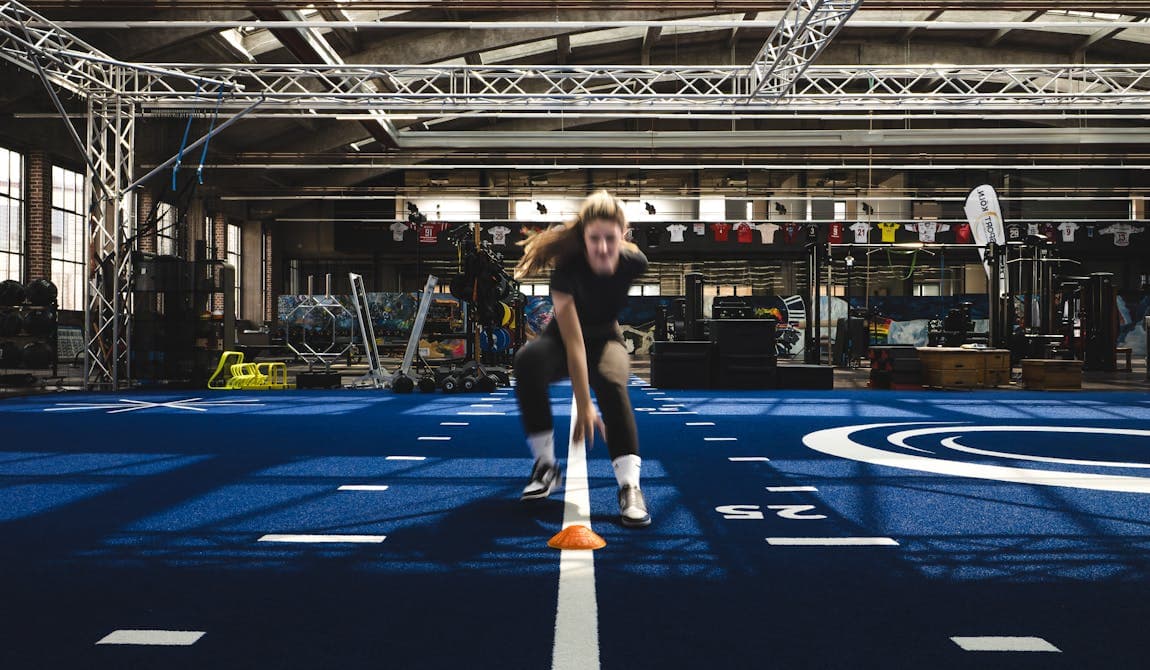 Sportlerin beim Sprint- und Koordinationstraining mit Hütchen in der Trainingshalle von Physiosport Köln.