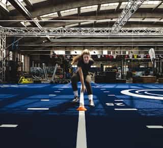 Sportlerin beim Sprint- und Koordinationstraining mit Hütchen in der Trainingshalle von Physiosport Köln.