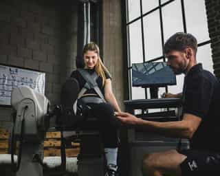 Trainer von PhysioSport Köln erläutert Sportlerin Kraftübungen für die Beinmuskulatur.