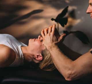 Patientin bei PhysioSport liegt entspannt auf Liege, Therapeut behandelt osteopathisch Kopf- und Stirnbereich.