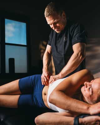 Trainer mobilisiert Hüftmuskulatur einer Patientin bei PhysioSport Köln.