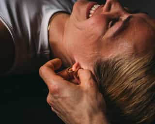 Patientin von PhysioSpost Köln wird an Triggerpunkten am Ohr behandelt.