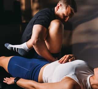 Patientin liegt bei PhysioSport auf Liege, männlicher Physiotherapeut korrigiert osteopathisch das Becken.