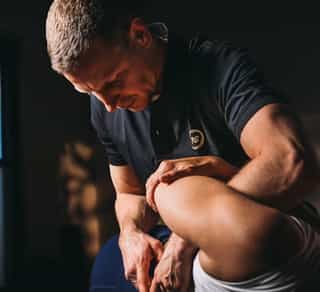 Liegende Patientin bei PhysioSport Köln, Therapeut korrigiert osteopathisch die Wirbelsäule.