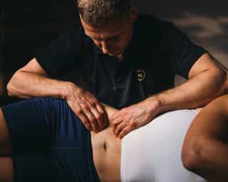 Trainer mobilisiert Hüftmuskulatur einer Patientin bei PhysioSport Köln.