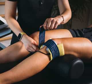 Kniebehandlung mit Elektroden in der Physikalischen Therapie bei PhysioSport, Physiotherapeutin unterstützt Patientin.