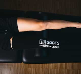 Patientin bei PhysioSport liegt auf Liege mit Kältemanschette am ganzen Bein zur Physikalischen Therapie.