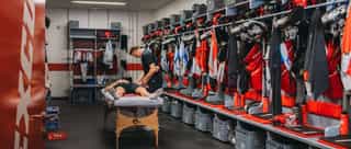 Zu sehen ist ein Einblick in die Mannschaftskabine der Kölner Haie, dem Partner von Physiosport Köln. In der Mitte steht eine Liege mit einem daraufliegendem Spieler, der behandelt wird.