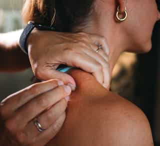 Osteopathie mit Dry Needling bei PhysioSport: Therapeutin prüft Muskelpunkte im Nacken einer Patientin.