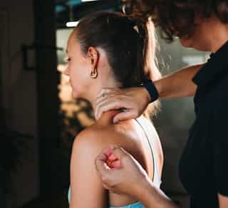 Osteopathie und Dry Needling bei PhysioSport: Therapeutin ertastet gezielt Triggerpunkte im Nacken für eine optimale Behandlung.