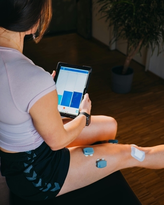 Physikalische Therapie mit EMG bei PhysioSport: Patientin mit Elektroden am Oberschenkel.