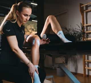 Physiotherapeutin von Physiosport Köln behandelt Knieverletzung in der Rehaphase einer Patientin.