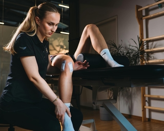 Physiotherapeutin von PhysioSport Köln behandelt Knieverletzung in der Rehaphase einer Patientin.