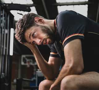Profisportler sitzt auf einer Bank bei PhysioSport Köln und grübelt über seine Rückenschmerzen nach Bandscheibenvorfall nach.
