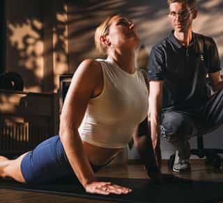 Physiotherapeut von PhysioSport Köln unterstützt Patientin bei krankengymnastischen Übungen.