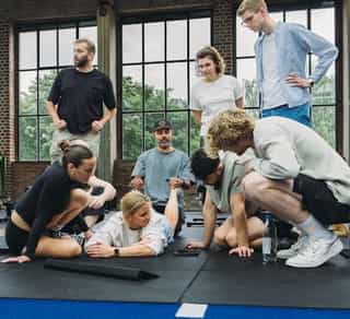 Gruppe von Patient:innen mit Trainer:innen von Physiosport bei einer Besprechung in der Trainingshalle
