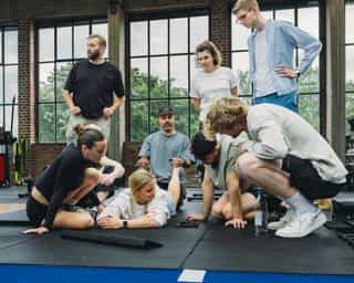 Gruppe von Patient:innen mit Trainer:innen von Physiosport bei einer Besprechung in der Trainingshalle