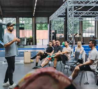 Trainer von PhysioSport bei einer Präsentation mit einer Gruppe von Patient:innen von Physiosport Köln.