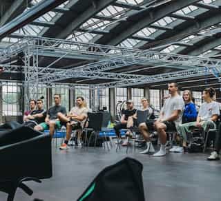 Zu sehen ist eine Trainerin von Physiosport, die einer Gruppe von Sportlern die Inhalte von PACE Athletiktraining theoretisch vermittelt.
