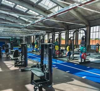 Blick in die Trainingshalle von Physiosport Köln. Zu sehen sind Geräte und Übungsstationen.