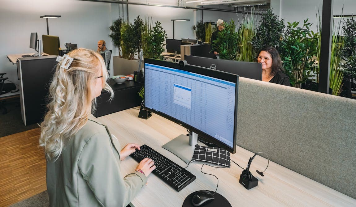 Zu sehen ist der Einblick in einen offenen Arbeitsplatz bei PhysioSport Köln. Dort sitzt eine Mitarbeiterin am Computer und im Hintergrund andere Arbeitsplätze.