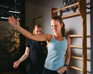 Zu sehen ist eine Physiotherapeutin von PhysioSport Köln bei der Behandlung einer Patientin mit Impingement Schulter. Painful arc.