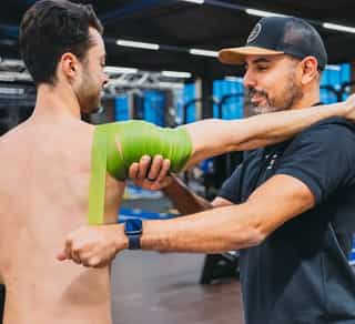 Sportler wird von einem Physiotherapeuten von PhysioSport Köln an der Schulter behandelt.