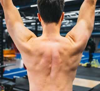 Zu sehen ist der kräftige Rücken und Schultermuskulatur eines Sportlers im Training bei PhysioSport Köln.