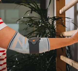 Zu sehen ist eine Sportlerin, die eine Behandlung eines Tennisellenbogens bei PhysioSport Köln bekommt.