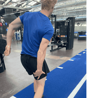 Man sieht einen Sportler bei PhysioSport Köln, der sich nach einer Muskelverletzung an sein Bein greift.