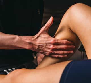 Physiotherapeut von PhysioSport Köln behandelt eine Sportlerin mit manueller Lymphdrainage im Wadenbereich.