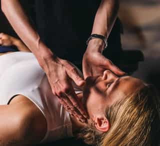 Physiotherapeut von PhysioSport Köln behandelt eine Sportlerin mit manueller Lymphdrainage am Kopfbereich.