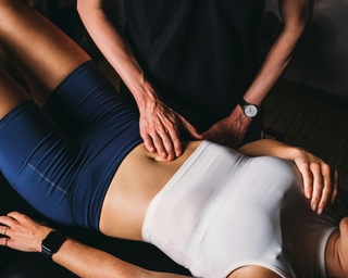 Physiotherapeut von PhysioSport Köln behandelt eine Sportlerin mit manueller Lymphdrainage im Rumpfbereich.