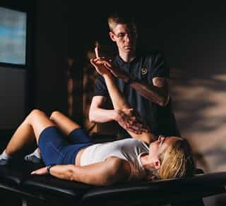 Physiotherapeut von PhysioSport Köln behandelt eine Patientin mit Krankengymnastik auf neurologischer Basis am rechten Arm.