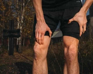 Sportler fasst sich ans Knie aufgrund von Knieschmerzen.